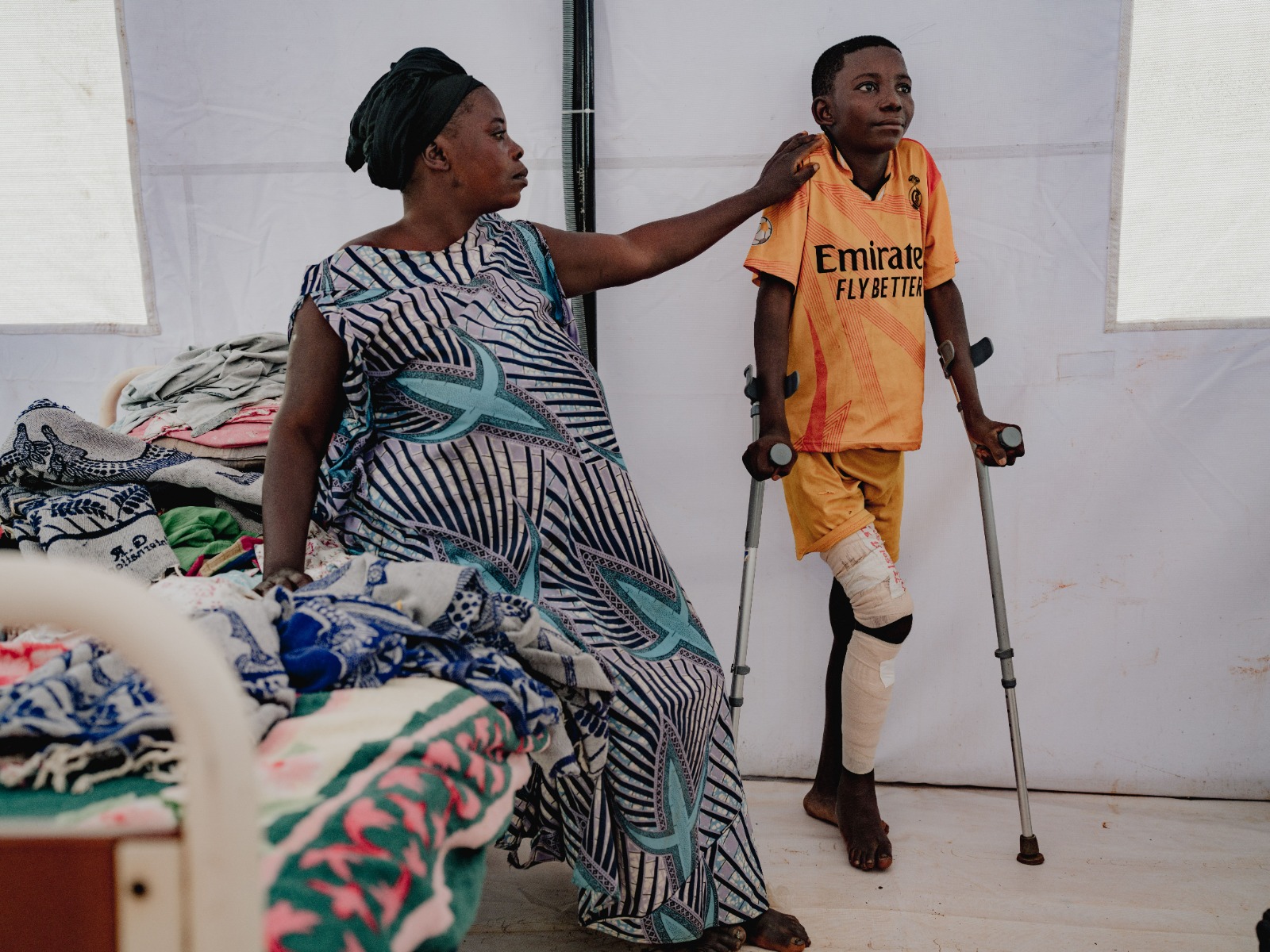 Hôpital Général de Référence de Fizi. Le fils d’Adela, âgé de 14 ans, a été blessé par balle à la jambe alors qu’il se réfugiait chez lui pour se protéger des combats dans son village de Kanguli. Fizi, province du Sud-Kivu, République démocratique du Congo, 20 mai 2026. ©Hugh Kinsella Cunningham